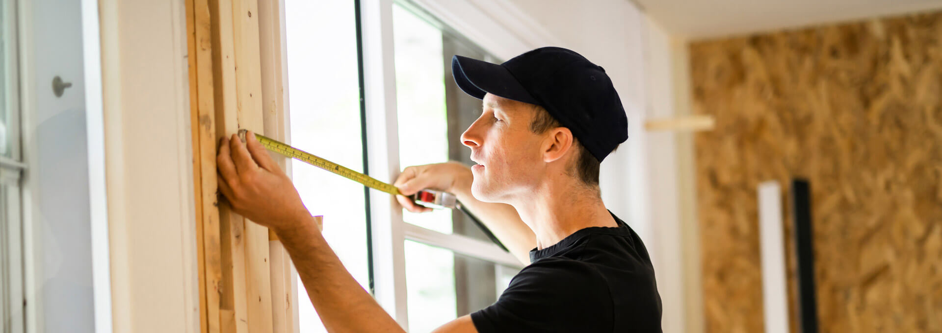 A window installer doing some final measurements before installing a replacement window.